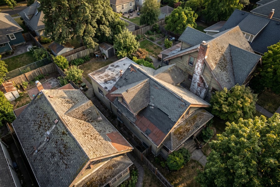 Insurance inspector examining the roof and exterior of a 30-year-old brick home